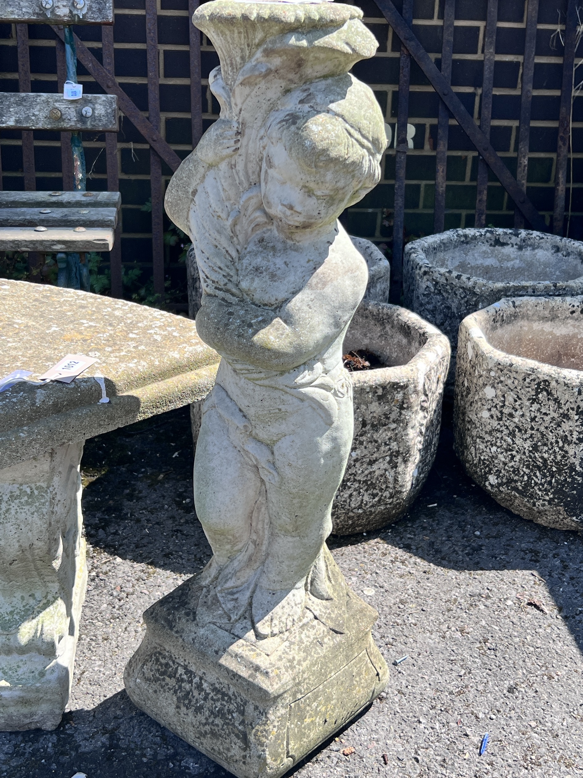 A small reconstituted stone curved garden bench, width 110cm, height 44cm, together with a stone pedestal and a small dog ornament